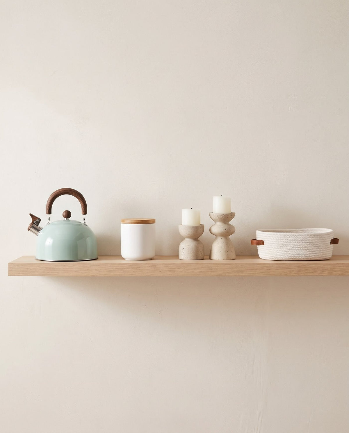 Kettle, storage jar, travertine candle holders and rope basket on a pale oak shelf